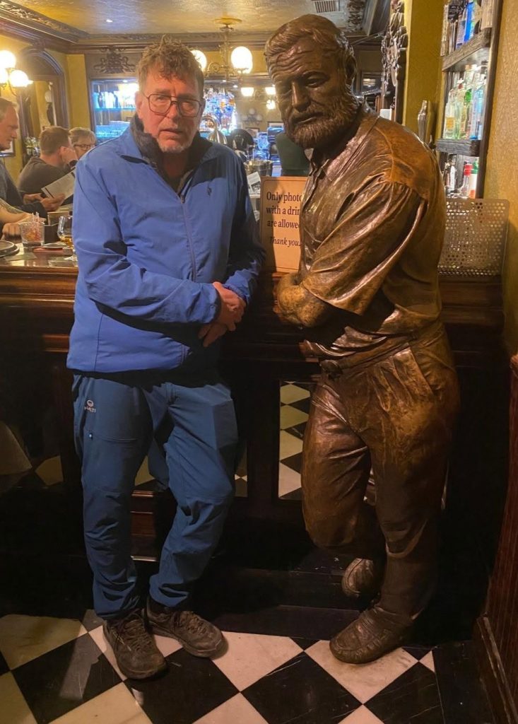 Kuva jossa mies seisso Enest Hemingwayn patsaan vieressä Ravintola Irunassa